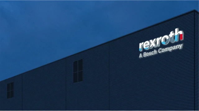 The Rexroth logo is displayed on a modern, gray corporate building as dusk settles, with a deep blue evening sky in the background.