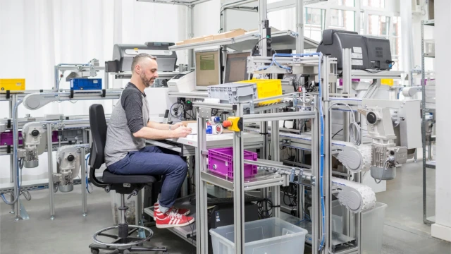 一名工人在工作台上操作，输送系统持续输送材料