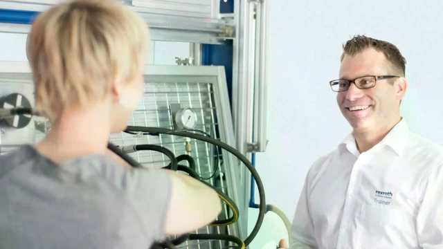 一位力士乐培训师正使用液压培训系统上的一套设备，讲解训练设置。 